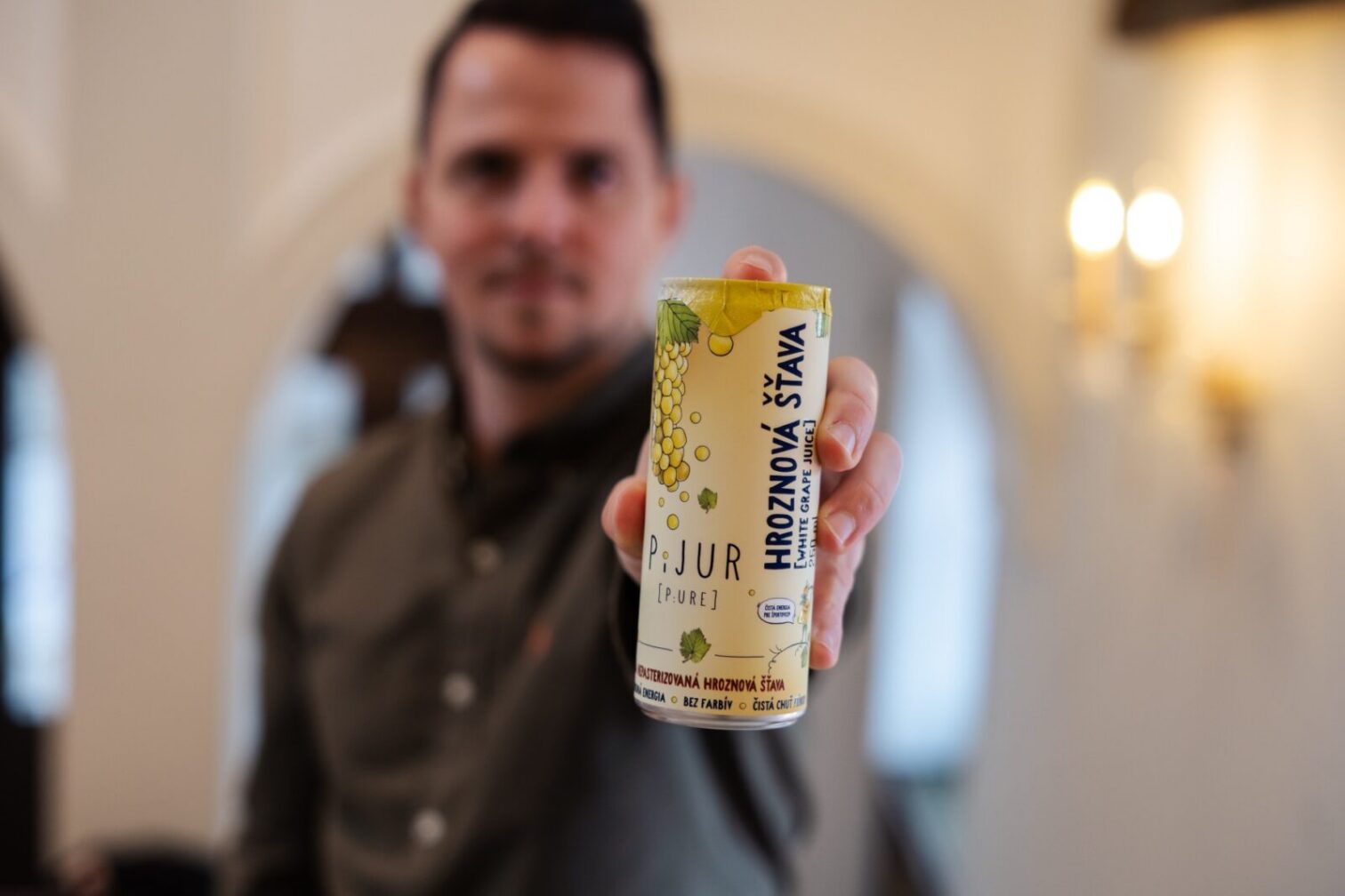 Osoba drží plechovku hroznového nápoja.